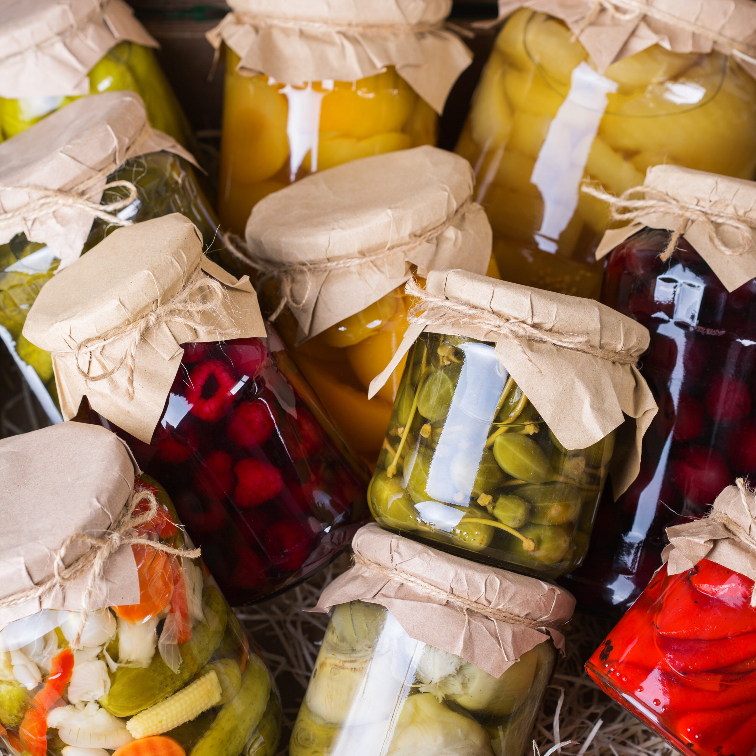 Preserved and fermented local food. Assortment of homemade jars with variety of pickled and marinated vegetables, fruit compote on a wooden table. Housekeeping, home economics, harvest preservation